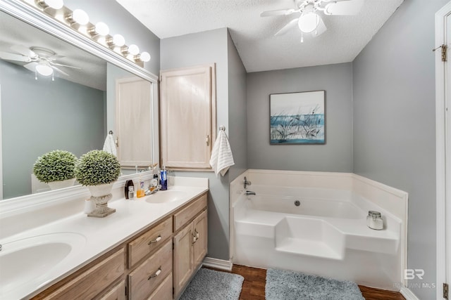 bathroom featuring a garden tub, a textured ceiling, and a sink