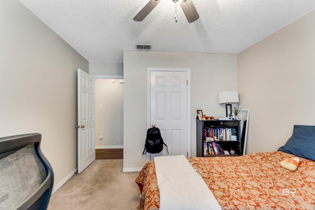 bedroom featuring a textured ceiling, light colored carpet, a ceiling fan, baseboards, and visible vents