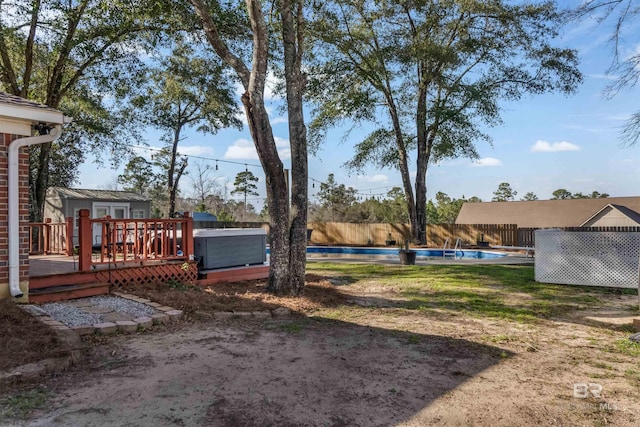 view of yard featuring a fenced backyard, a deck, a fenced in pool, and an outbuilding