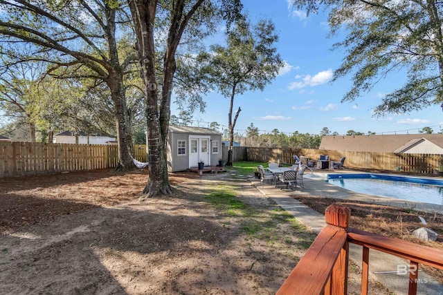 view of yard featuring a fenced backyard, a storage shed, an outdoor structure, a fenced in pool, and a patio area