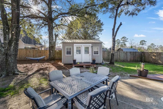 view of patio / terrace featuring a fenced backyard, a storage unit, outdoor dining area, and an outdoor structure