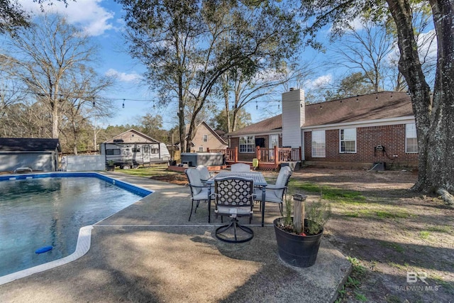 view of swimming pool with a fenced in pool, an outbuilding, outdoor dining area, a patio, and a wooden deck