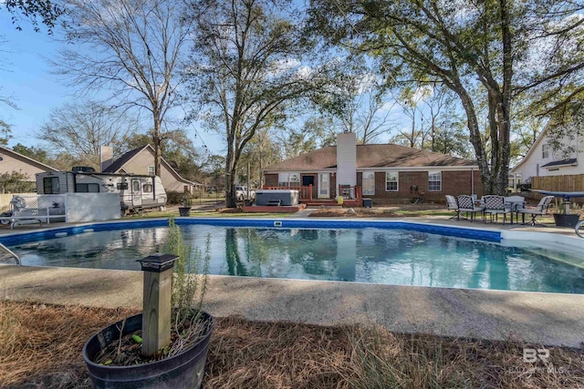 pool with a patio area, fence, and a jacuzzi