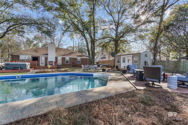 view of pool with an outbuilding, fence, a wooden deck, a fenced in pool, and a hot tub