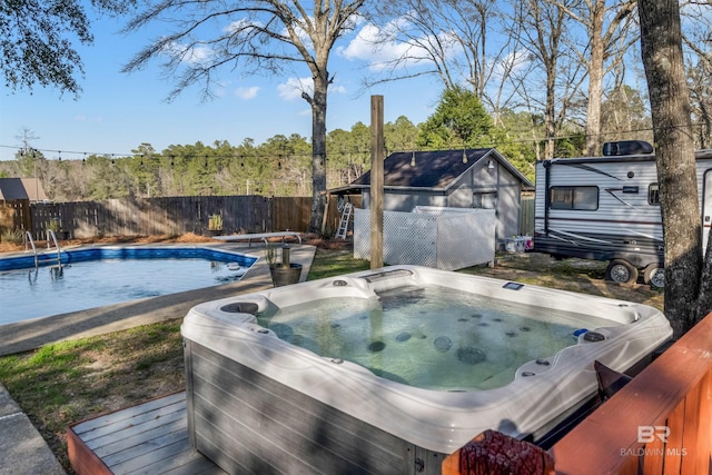 view of swimming pool featuring an outdoor structure, fence, a diving board, a fenced in pool, and a hot tub