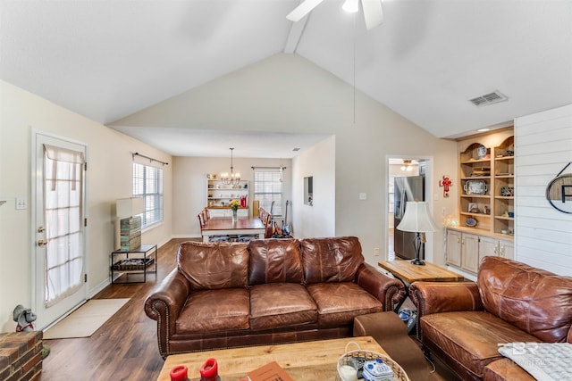 living area with ceiling fan with notable chandelier, wood finished floors, visible vents, and lofted ceiling