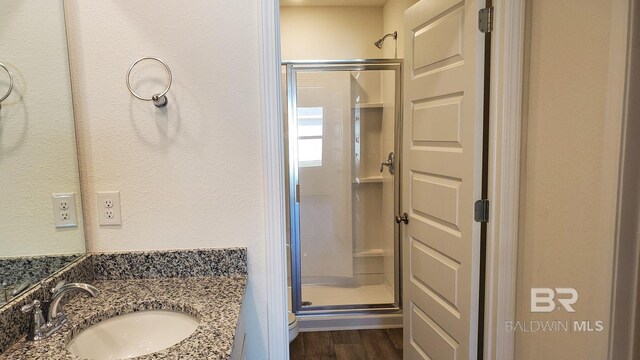 bathroom with hardwood / wood-style floors, toilet, walk in shower, and vanity