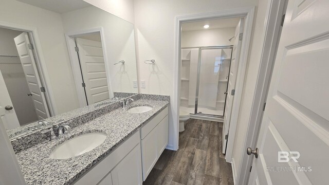 bathroom featuring toilet, wood-type flooring, a shower with door, and vanity