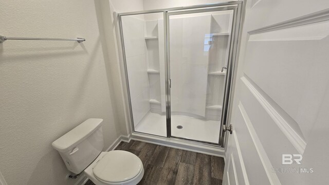 bathroom featuring toilet, wood-type flooring, and an enclosed shower