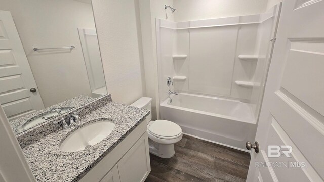 full bathroom featuring wood-type flooring, washtub / shower combination, vanity, and toilet