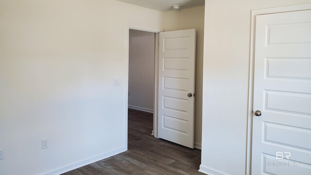 unfurnished room with dark wood-type flooring