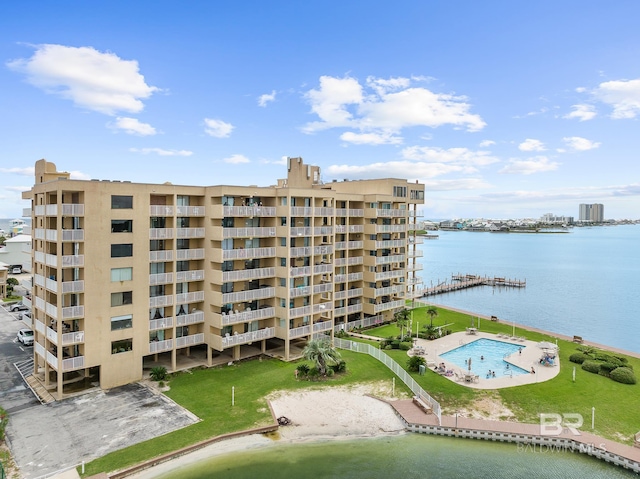 view of building exterior with a community pool and a water view