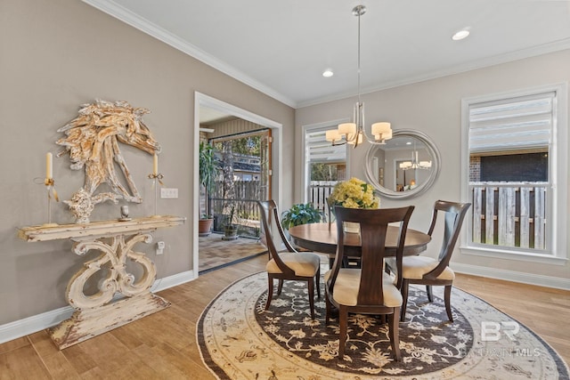 dining space with baseboards, wood finished floors, an inviting chandelier, crown molding, and recessed lighting