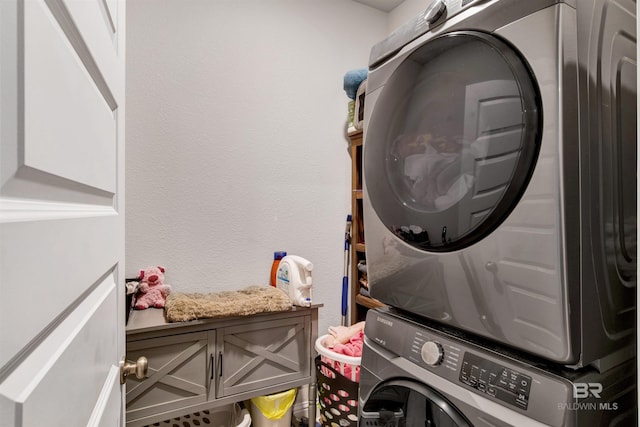 laundry area with stacked washer and clothes dryer and a textured wall