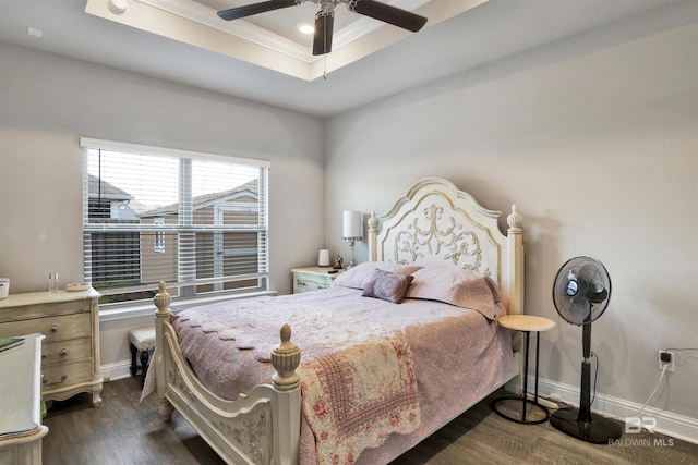 bedroom featuring a ceiling fan, baseboards, a tray ceiling, dark wood-style flooring, and ornamental molding