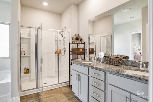 ensuite bathroom featuring visible vents, a stall shower, wood finished floors, and a sink