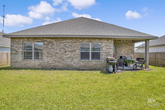 back of property with brick siding, a patio area, a yard, and fence