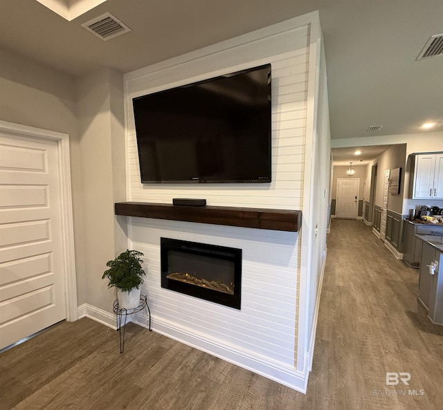 unfurnished living room with a glass covered fireplace, wood finished floors, and visible vents