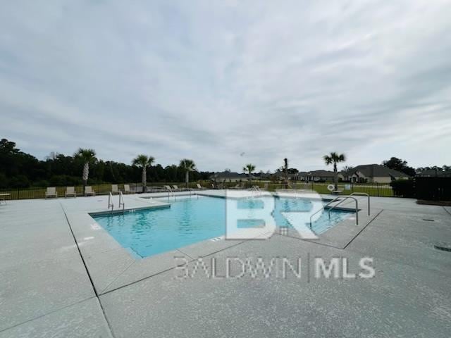 pool with a patio area and fence