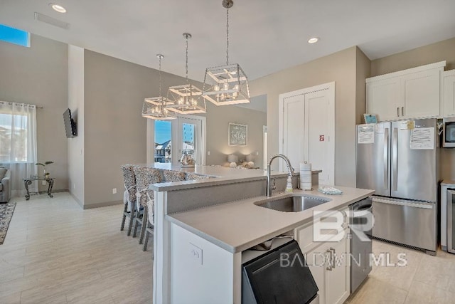 kitchen with sink, an island with sink, decorative light fixtures, white cabinetry, and stainless steel appliances