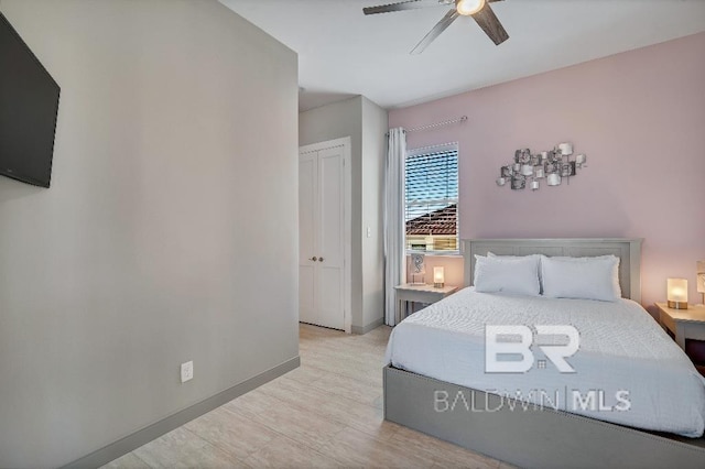 bedroom with a closet, light hardwood / wood-style floors, and ceiling fan