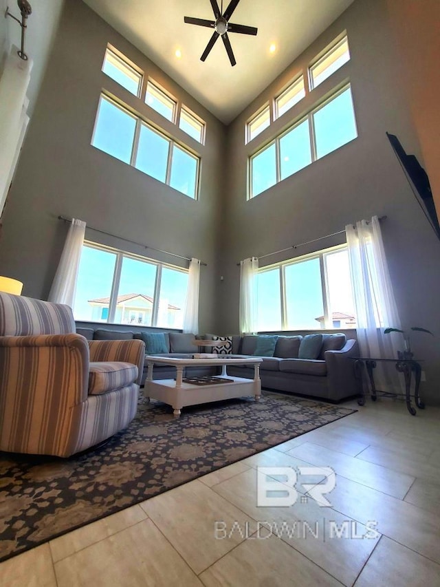living room with tile patterned flooring, a towering ceiling, and ceiling fan
