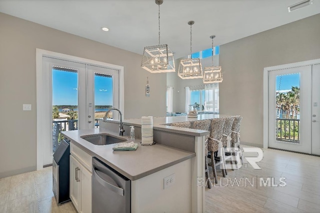 kitchen featuring french doors, dishwasher, sink, a center island with sink, and white cabinets