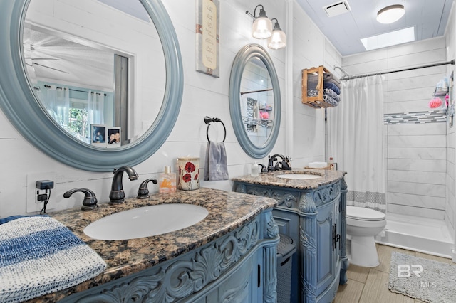 bathroom with curtained shower, vanity, toilet, and a skylight