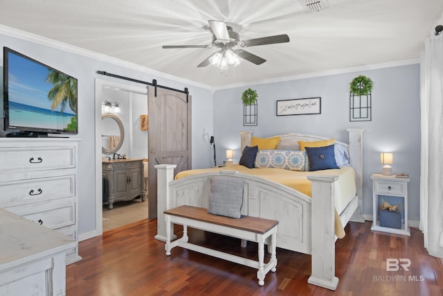 bedroom featuring ensuite bath, ornamental molding, dark hardwood / wood-style floors, ceiling fan, and a barn door