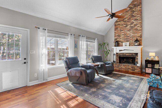 living room with wood-type flooring, high vaulted ceiling, ceiling fan, and a fireplace