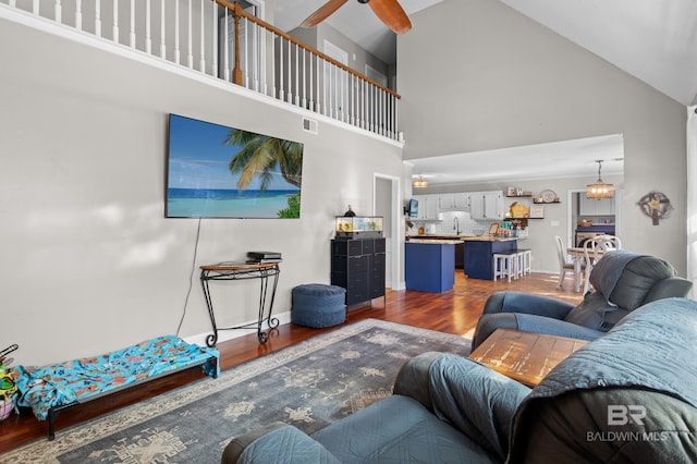 living room with hardwood / wood-style flooring, high vaulted ceiling, and ceiling fan with notable chandelier