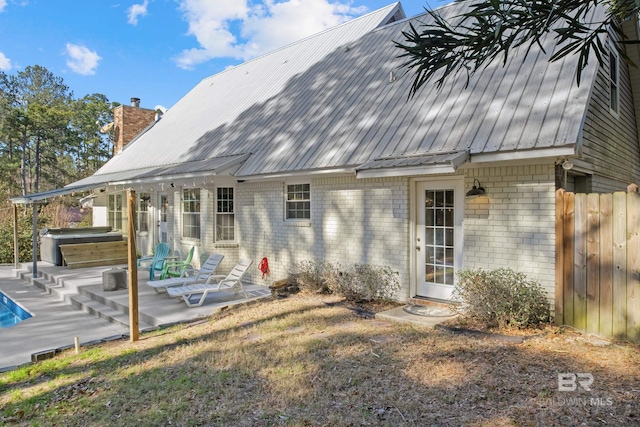 back of property with a patio area and a hot tub