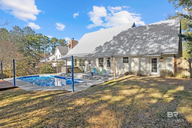 back of property with a hot tub, a patio area, and a lawn