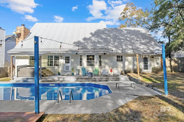 rear view of property featuring a pool with hot tub and a patio area