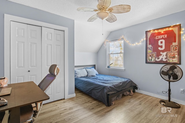 bedroom featuring a closet, vaulted ceiling, light hardwood / wood-style flooring, and a textured ceiling