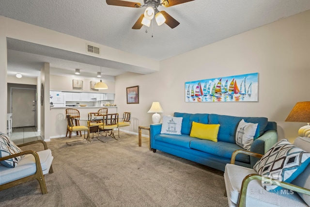 living room with ceiling fan, carpet floors, and a textured ceiling