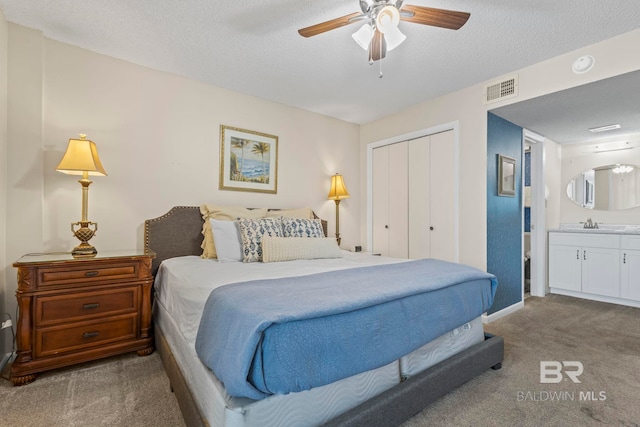 carpeted bedroom featuring ceiling fan, a textured ceiling, a closet, and connected bathroom