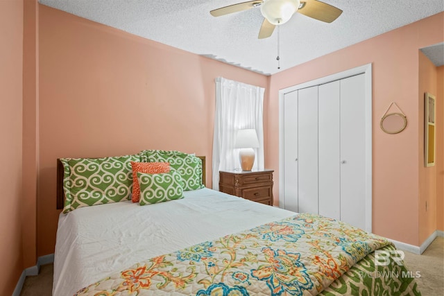 carpeted bedroom with ceiling fan, a closet, and a textured ceiling