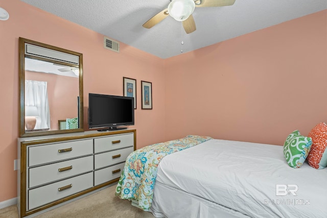 carpeted bedroom with ceiling fan and a textured ceiling