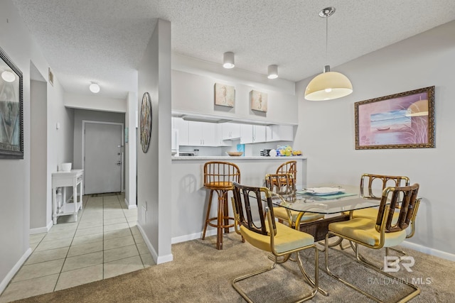 dining room featuring light colored carpet and a textured ceiling