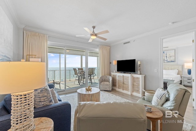 living room featuring ceiling fan, crown molding, and light hardwood / wood-style flooring