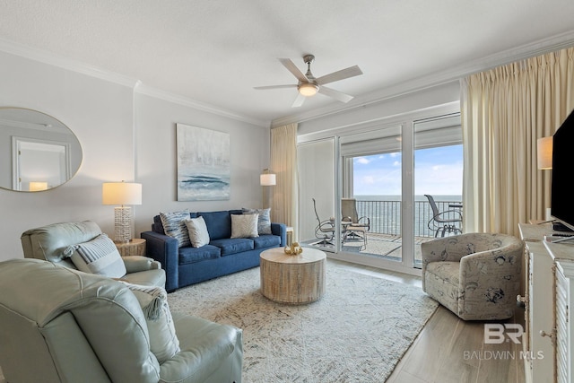 living room featuring light hardwood / wood-style floors, ceiling fan, ornamental molding, and a water view