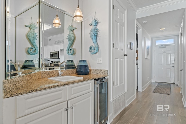 bathroom featuring wood-type flooring, vanity, beverage cooler, and crown molding