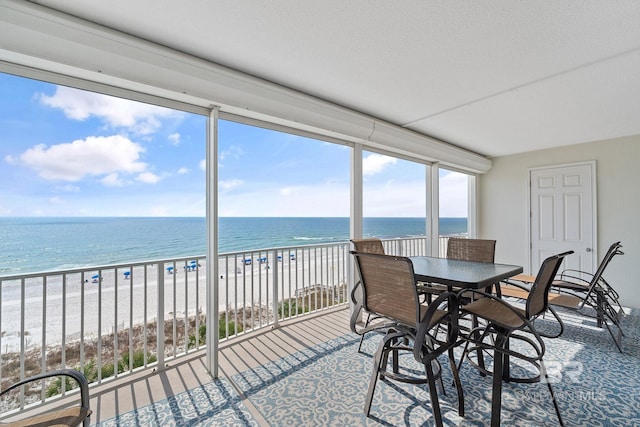 sunroom with a water view and a beach view