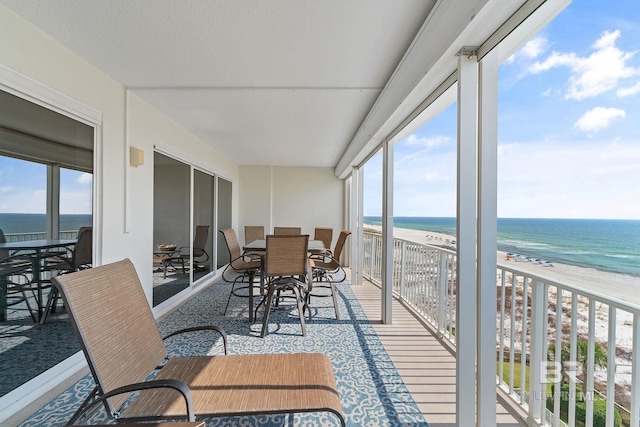 sunroom featuring a water view, a healthy amount of sunlight, and a beach view