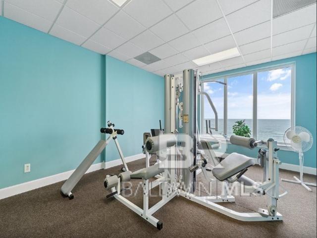 exercise room featuring a paneled ceiling and a water view