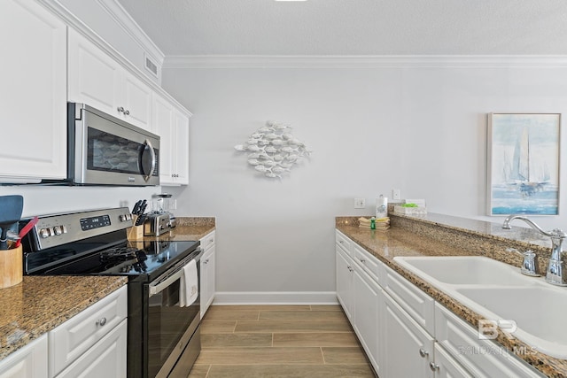 kitchen featuring white cabinetry, sink, light hardwood / wood-style flooring, appliances with stainless steel finishes, and ornamental molding