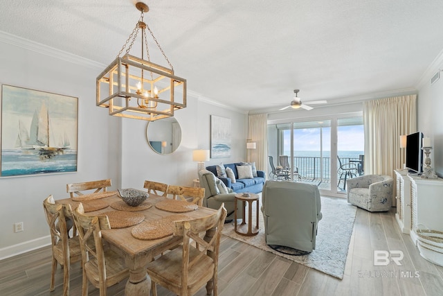 dining room featuring hardwood / wood-style flooring, ceiling fan with notable chandelier, crown molding, and a textured ceiling