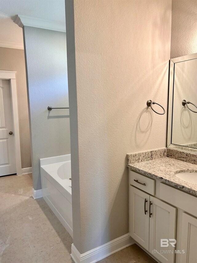 bathroom with a tub, vanity, and ornamental molding