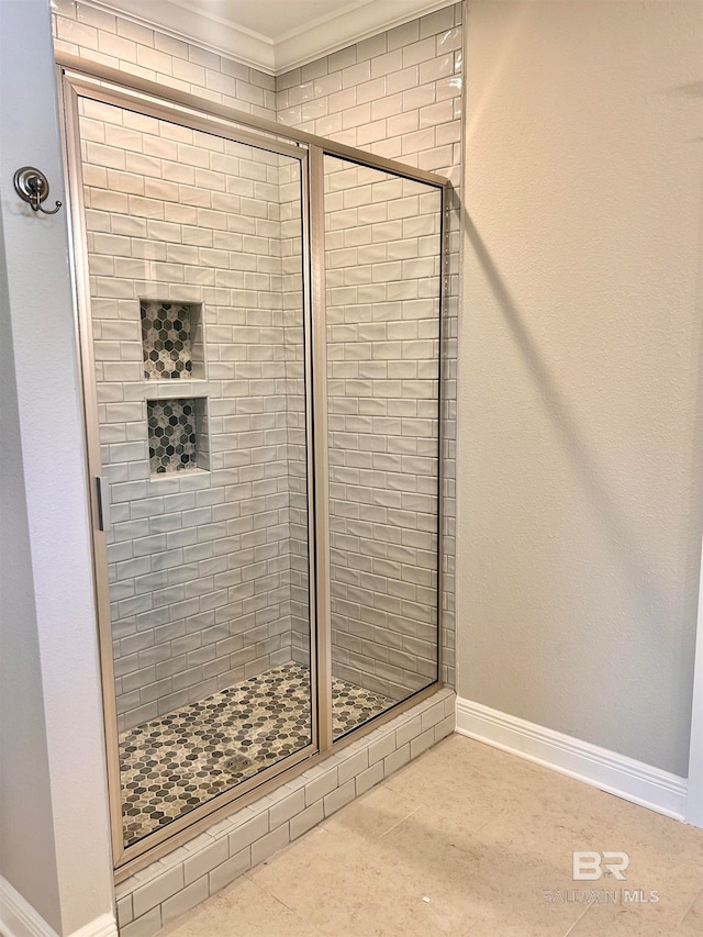 bathroom with a shower with shower door and ornamental molding